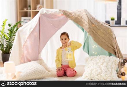 childhood and hygge concept - happy little girl with christmas lantern in kids tent at home. little girl with lantern in kids tent at home. little girl with lantern in kids tent at home
