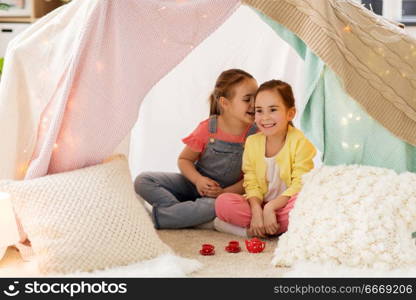 childhood and hygge concept - happy little girls playing tea party with toy crockery in kids tent at home and sharing secrets. little girl playing tea party in kids tent at home. little girl playing tea party in kids tent at home