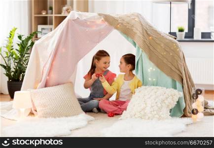 childhood and hygge concept - happy little girls playing tea party with toy crockery in kids tent at home. little girl playing tea party in kids tent at home. little girl playing tea party in kids tent at home