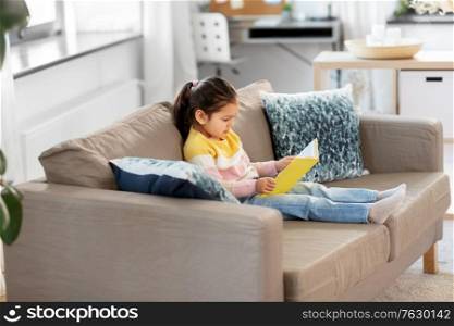 childhood and leisure concept - little girl reading book at home. little girl reading book at home