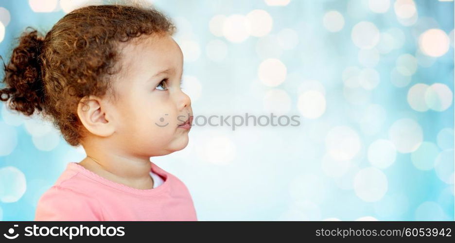 childhood and people concept - beautiful african american little baby girl portrait over blue holidays lights background. beautiful little baby girl portrait