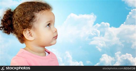 childhood and people concept - beautiful african american little baby girl portrait over blue sky and clouds background. beautiful little baby girl portrait