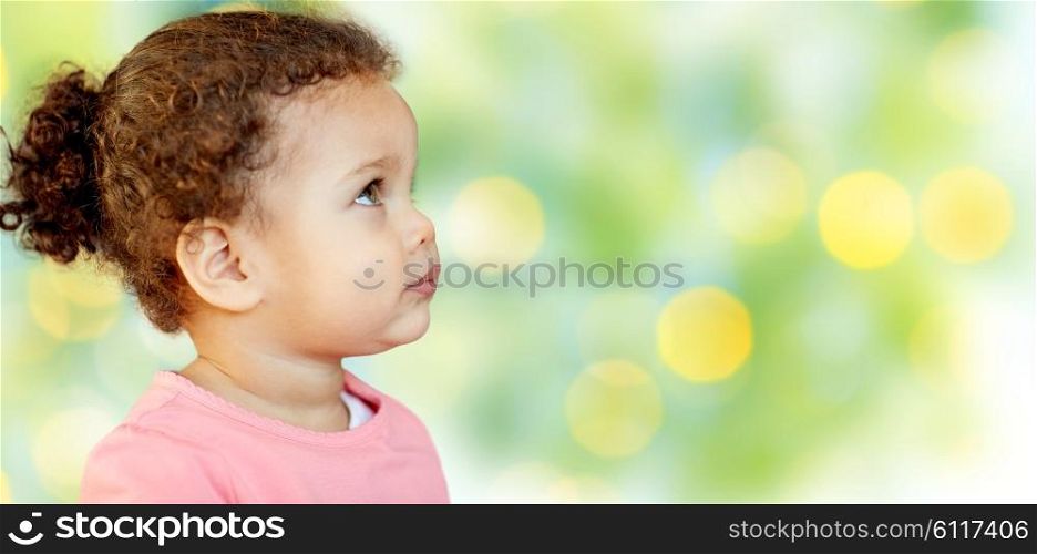 childhood and people concept - beautiful african american little baby girl portrait over green lights background. beautiful little baby girl portrait
