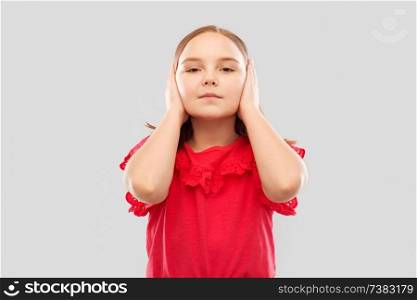 childhood and people concept - beautiful girl in red shirt closing ears by hands over grey background. beautiful girl in red shirt closing ears by hands