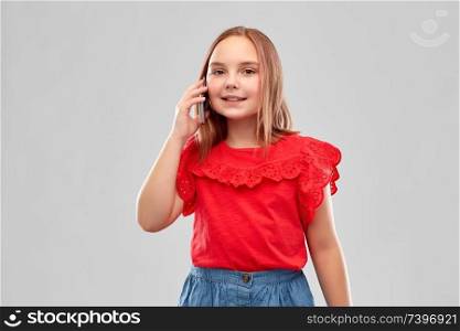 childhood and people concept - beautiful smiling girl in red shirt and skirt calling on smartphone over grey background. beautiful smiling girl calling on smartphone