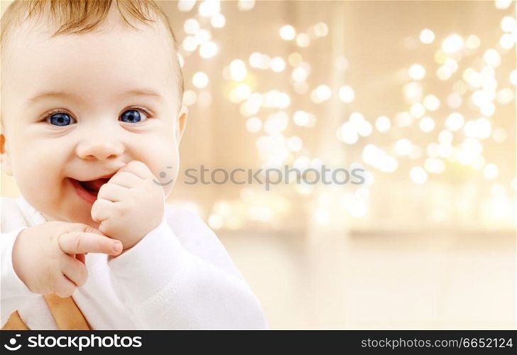 childhood and people concept - close up of sweet little baby over christmas lights background. close up of sweet baby over christmas lights