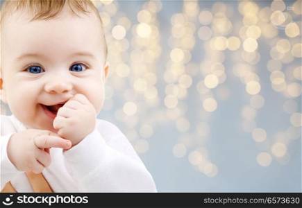 childhood and people concept - close up of sweet little baby over festive lights background. close up of little baby over lights background