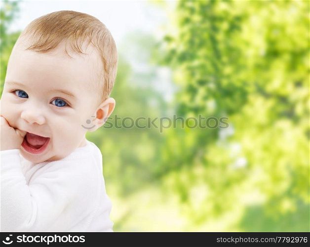 childhood and people concept - close up of sweet little baby over green natural background. close up of sweet little baby