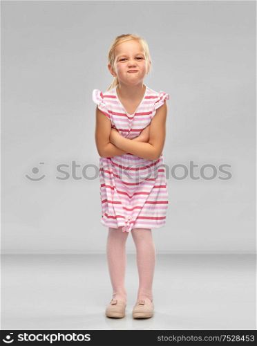 childhood and people concept - displeased little girl in red shirt with crossed arms pouting over grey background. displeased little girl with crossed arms pouting