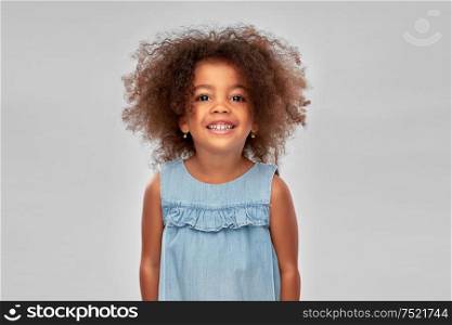 childhood and people concept - happy little african american girl over grey background. happy little african american girl over grey