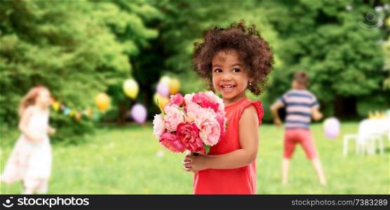 childhood and people concept - happy little african american girl with flowers at birthday party over summer park background. happy little african american girl with flowers
