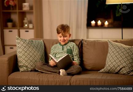 childhood and people concept - happy little boy reading book at home. happy little boy reading book at home