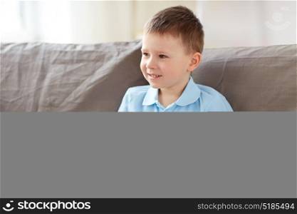 childhood and people concept - happy little boy with toy car sitting on sofa at home. happy little boy with toy car at home