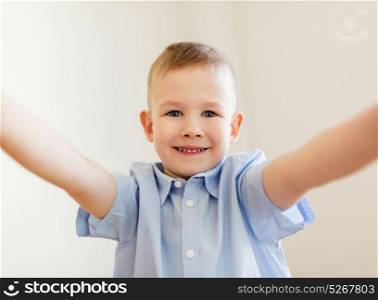 childhood and people concept - happy smiling little boy taking selfie. happy smiling little boy taking selfie