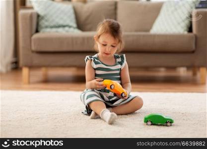 childhood and people concept - happy three years old baby girl playing with toy car at home. happy baby girl playing with toy car at home