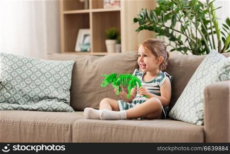 childhood and people concept - happy three years old baby girl playing with toy dinosaur skeleton at home. happy baby girl playing with toy dinosaur at home