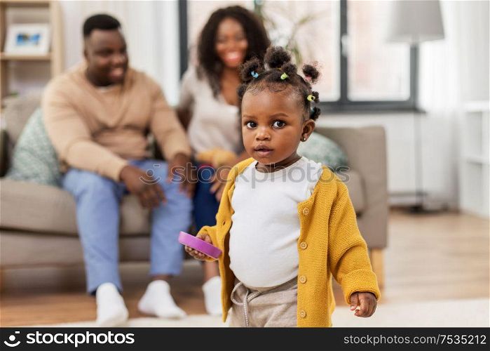 childhood and people concept - little african american baby girl playing with toy blocks and parents at home. african baby girl playing with toy blocks at home