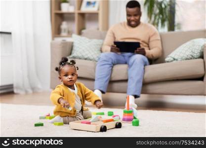 childhood and people concept - little african american baby girl playing with toy blocks at home. african baby girl playing with toy blocks at home