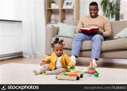childhood and people concept - little african american baby girl playing with toy blocks at home. african baby girl playing with toy blocks at home