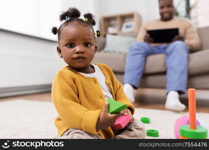 childhood and people concept - little african american baby girl playing with toy blocks at home. african baby girl playing with toy blocks at home