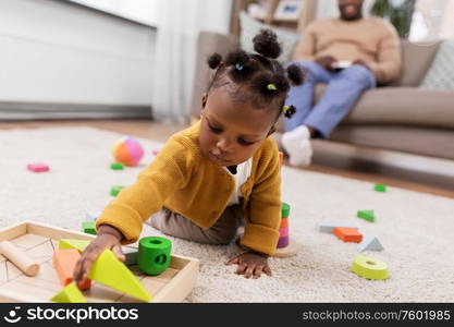 childhood and people concept - little african american baby girl playing with toy blocks at home. african baby girl playing with toy blocks at home