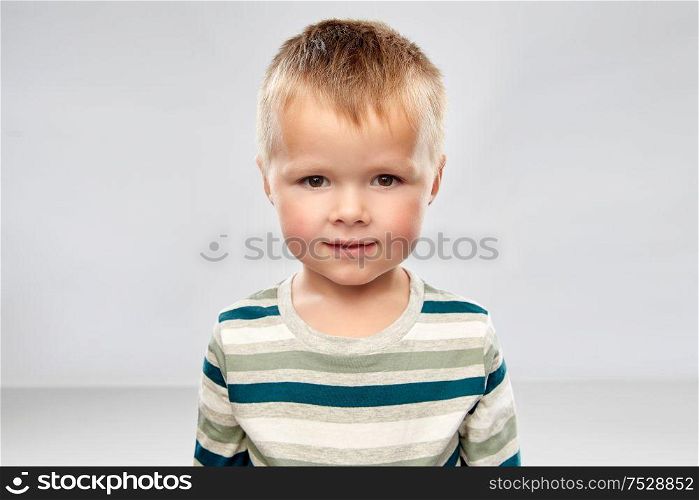 childhood and people concept - portrait of little boy in striped shirt over grey background. portrait of little boy in striped shirt