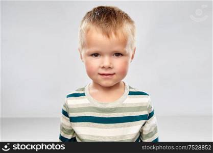 childhood and people concept - portrait of little boy in striped shirt over grey background. portrait of little boy in striped shirt
