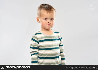 childhood and people concept - portrait of sad little boy in striped shirt over grey background. portrait of sad little boy in striped shirt