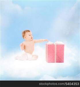childhood and present concept - smiling baby sitting on the cloud with big gift box