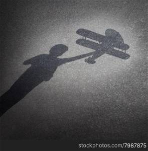 Childhood aspirations concept as a cast shadow on pavement of a child playing with a toy plane as a symbol for dreaming and imagination through fun and learning as a happy kid.