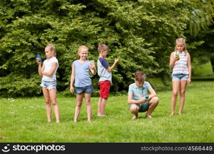childhood, augmented reality, internet addiction, technology and people concept - group of kids or friends with smartphones playing game in summer park