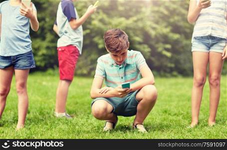 childhood, augmented reality, internet addiction, technology and people concept - group of kids or friends with smartphones playing game in summer park. kids with smartphones playing game in summer park