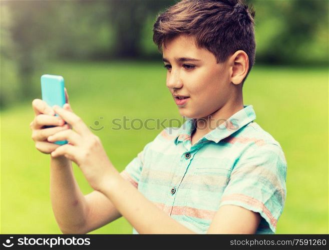 childhood, augmented reality, technology and people concept - boy with smartphone playing game in summer park. boy with smartphone playing game in summer park