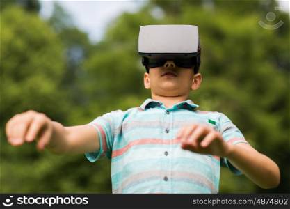 childhood, augmented reality, technology and people concept - boy with virtual headset or 3d glasses playing game outdoors at summer. boy with virtual reality headset outdoors