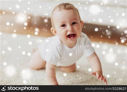 childhood, babyhood and people concept - happy smiling little baby boy or girl crawling on floor at home over snow. little baby in diaper crawling on floor at home