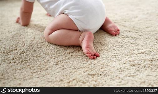 childhood, babyhood and people concept - little baby boy or girl crawling on floor at home