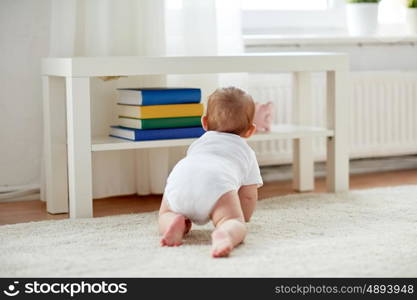 childhood, babyhood and people concept - little baby boy or girl crawling on floor at home