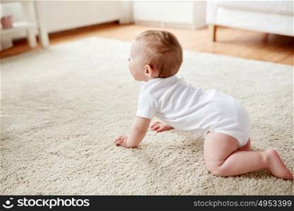 childhood, babyhood and people concept - little baby boy or girl crawling on floor at home. little baby in diaper crawling on floor at home