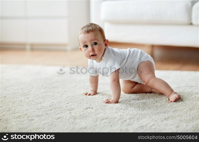 childhood, babyhood and people concept - little baby boy or girl crawling on floor at home. little baby in diaper crawling on floor at home