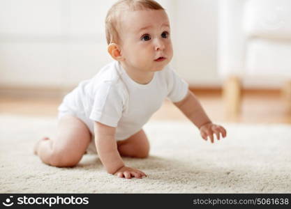 childhood, babyhood and people concept - little baby boy or girl crawling on floor at home. little baby in diaper crawling on floor at home