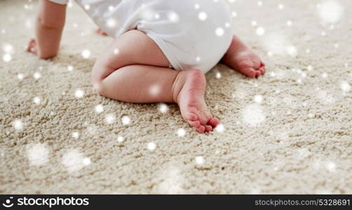 childhood, babyhood and people concept - little baby boy or girl crawling on floor over snow. little baby in diaper crawling on floor