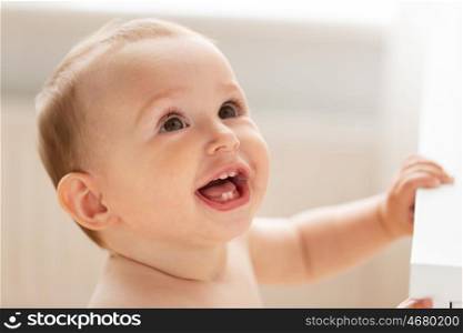 childhood, babyhood, emotions and people concept - close up of happy little baby boy or girl at home looking up