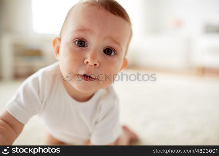 childhood, babyhood, emotions and people concept - close up of happy little baby boy or girl at home