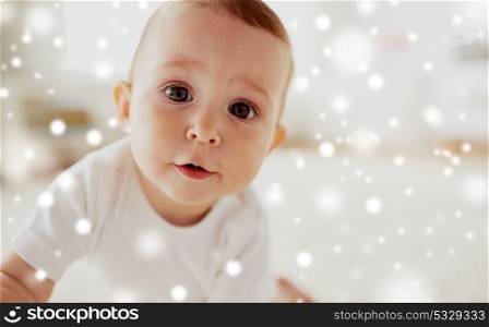childhood, babyhood, emotions and people concept - close up of happy little baby boy or girl over snow. close up of happy little baby boy or girl