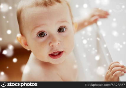 childhood, babyhood, emotions and people concept - face of happy little baby boy or girl holding to table over snow. face of happy little baby boy or girl