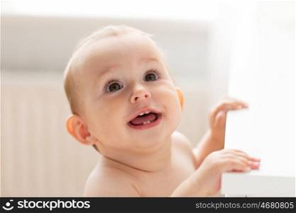 childhood, babyhood, emotions and people concept - happy little baby boy or girl at home looking up