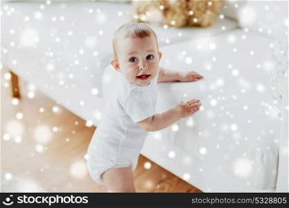childhood, babyhood, emotions and people concept - happy little baby boy or girl at home over snow. happy little baby boy or girl at home