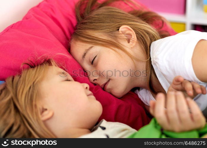 childhood, bedtime and family concept - happy little girls or sisters sleeping in bed at home. happy little girls sleeping in bed at home. happy little girls sleeping in bed at home