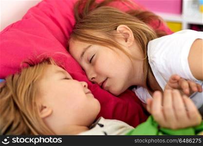 childhood, bedtime and family concept - happy little girls or sisters sleeping in bed at home. happy little girls sleeping in bed at home. happy little girls sleeping in bed at home