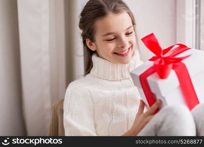 childhood, birthday, holidays and people concept - happy beautiful girl with christmas gift box at home. happy beautiful girl with christmas gift at home